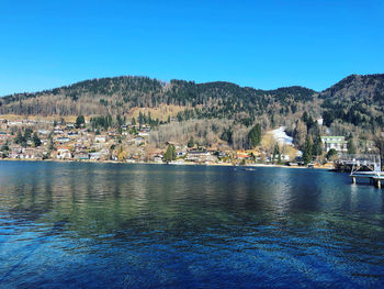 Scenic view of lake and buildings against clear blue sky