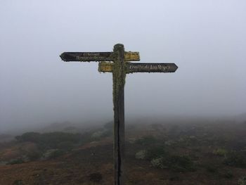 Cross on land against sky