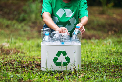 A woman collecting and putting plastic bottles into a recycle bin in the outdoors