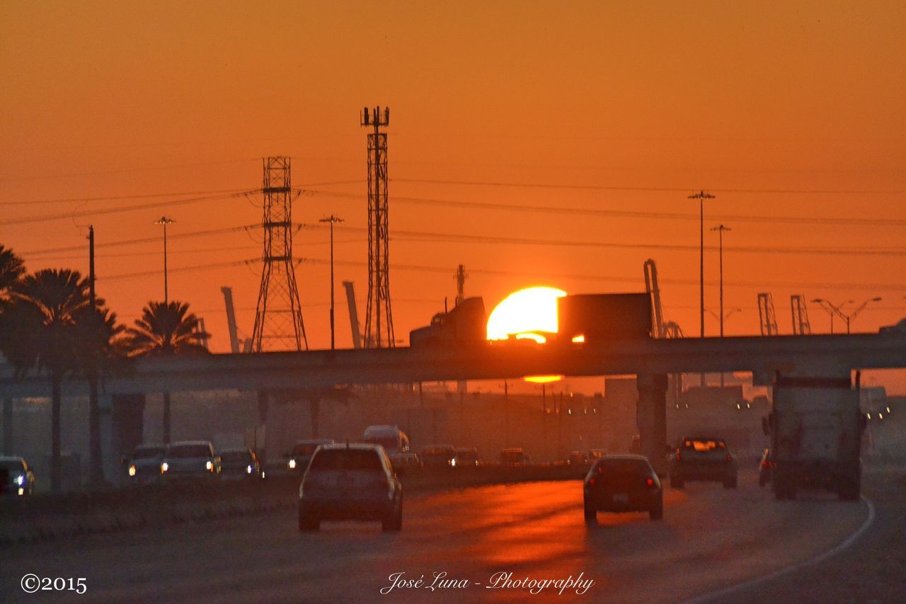 sunset, orange color, transportation, electricity pylon, power line, mode of transport, car, land vehicle, power supply, silhouette, electricity, sun, cable, road, clear sky, connection, street, sky, street light, built structure