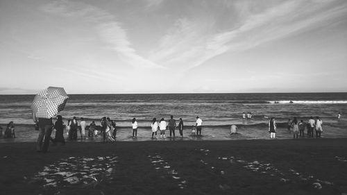 Group of people on beach against sky