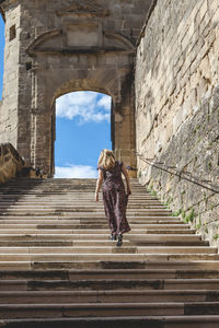 Woman in a long dress is climbing the steps of the abbey of saint antoine france