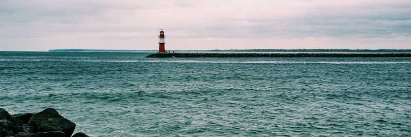 Lighthouse by sea against sky