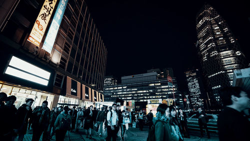 People on illuminated buildings in city at night