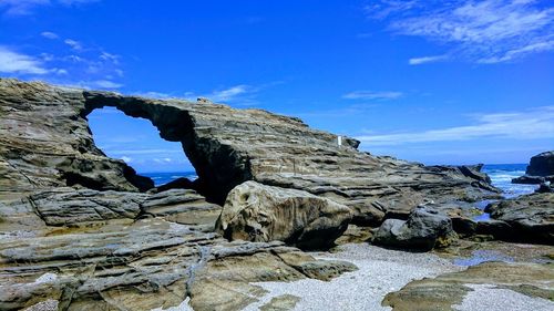 Rock formations on shore against blue sky