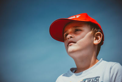 Low angle photo of a young boy with cap on looking away.