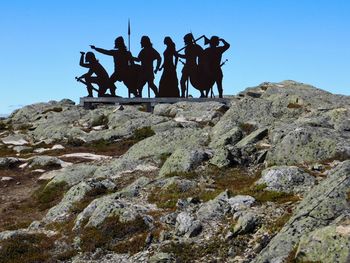 Low angle view of people on rock against sky