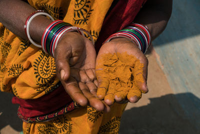 Midsection of woman with turmeric powder on hand