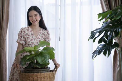 Young woman smiling while standing against window