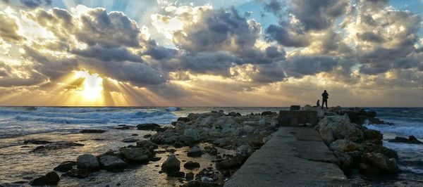 View of beach against cloudy sky during sunset