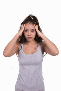 Portrait of young woman standing against white background