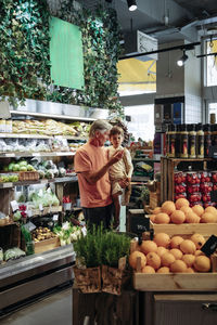 Grandfather talking with grandson while standing in supermarket