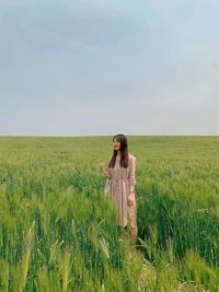 Young woman standing in agricultural field against sky