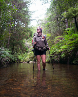 Full length of woman walking in river at forest