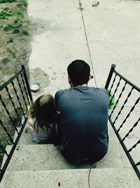 Rear view of man sitting with daughter on steps