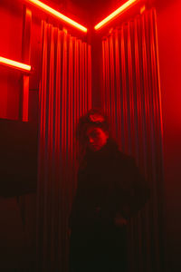Full length of woman standing in illuminated dark room