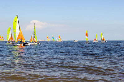 Sailboats in sea against sky