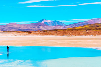 Scenic view of lake by mountains against blue sky