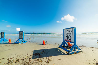 Information sign on beach against sky