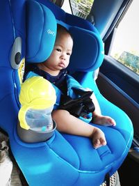 Cute baby boy sitting in toy car