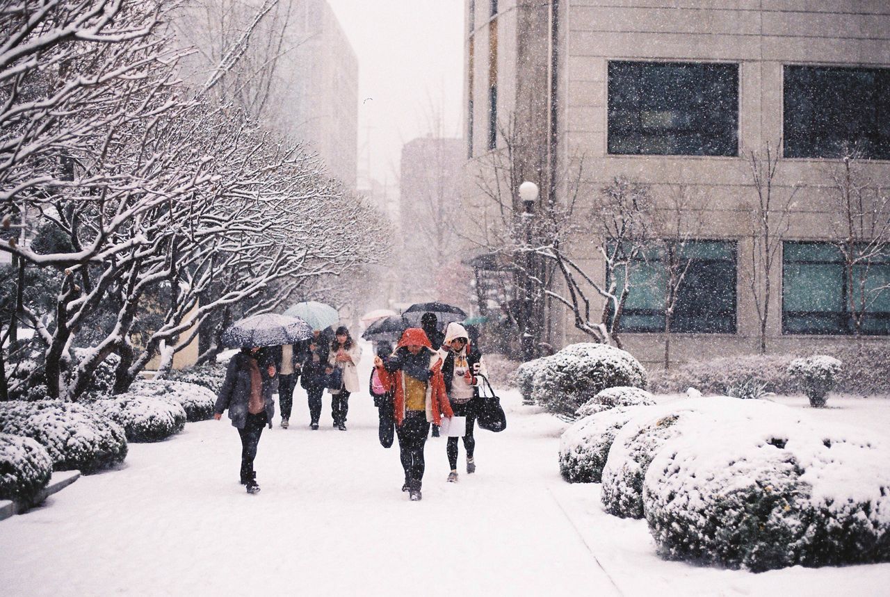 PEOPLE WALKING IN SNOW COVERED CITY