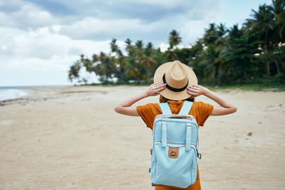 Rear view of woman wearing hat standing on beach