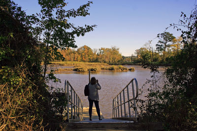 Rear view of woman looking at lake against sky