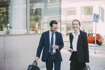 Happy male and female professionals in city