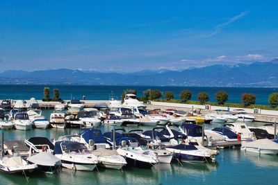 Boats moored at harbor against blue sky