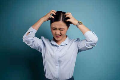 Young woman standing against blue background
