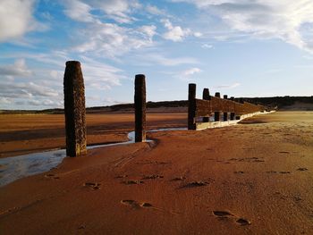 Wooden posts on beach against sky