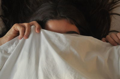 Close-up of woman lying on bed and covering face with fabric