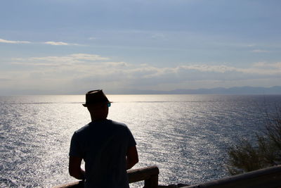 Rear view of man looking at sea against sky