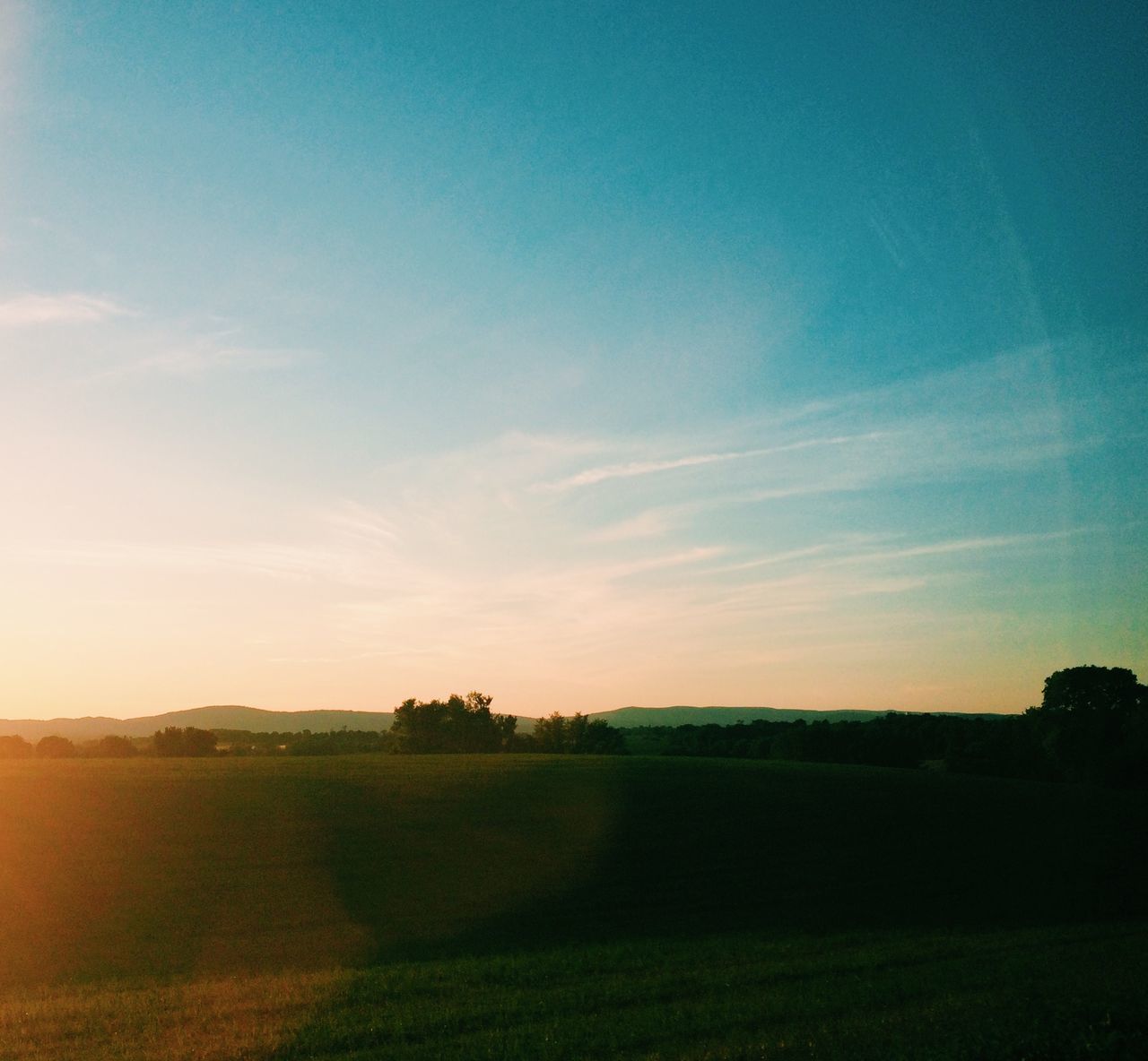 landscape, field, tranquil scene, tranquility, sky, scenics, rural scene, beauty in nature, grass, agriculture, nature, sunset, horizon over land, farm, blue, tree, idyllic, grassy, sunlight, cloud - sky