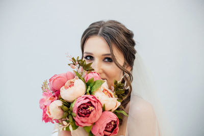 Portrait of woman with pink roses against white background