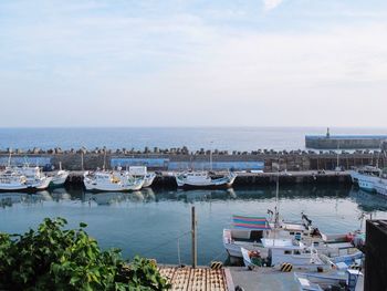 Boats moored at harbor against sky