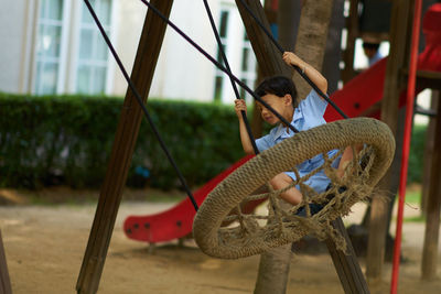 Cute boy sitting on swing at playground