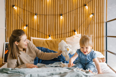 Mom and daughter are having fun on the bed and smiling. family time at home