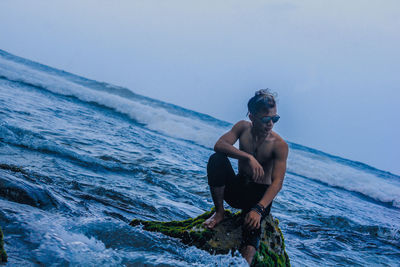 Young man in sea against sky