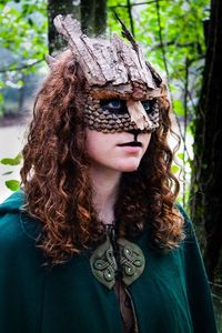 Close-up portrait of young woman wearing tree trunk