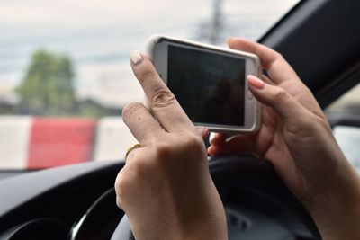 Close-up of woman using mobile phone in car