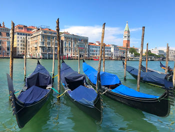 Gondolas moored in canal amidst buildings in city