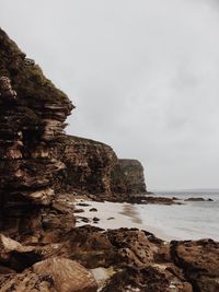 Scenic view of cliff by sea against sky