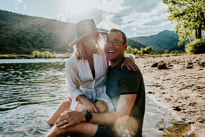 Portrait of a young couple hugging and laughing on lakeshore