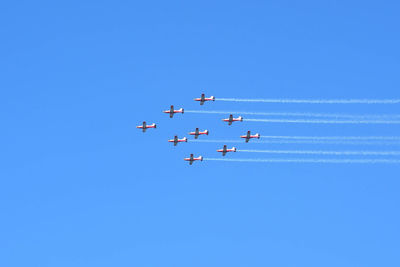 Low angle view of airshow against clear blue sky