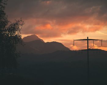 Scenic view of silhouette mountains against orange sky