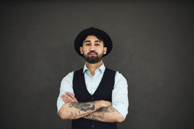 Portrait of young man standing against black background