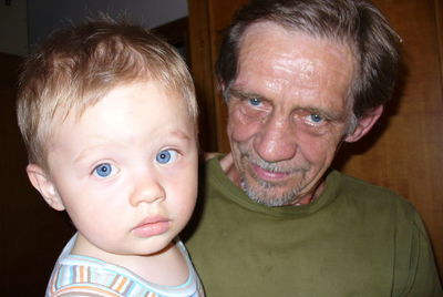 Close-up portrait of grandfather carrying grandson at home