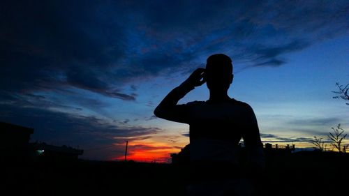 Silhouette man photographing at sunset