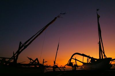 Low angle view of silhouette cranes against sky during sunset